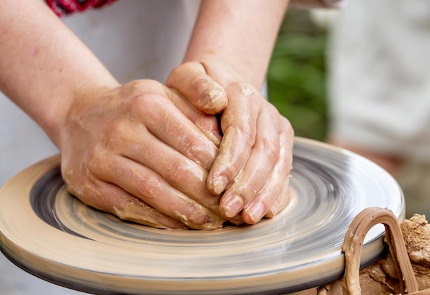 Le mani fanno la ceramica su un tornio da vasaio.