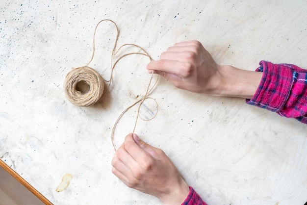 Le mani fanno un nodo di una corda spessa con una palla di corda