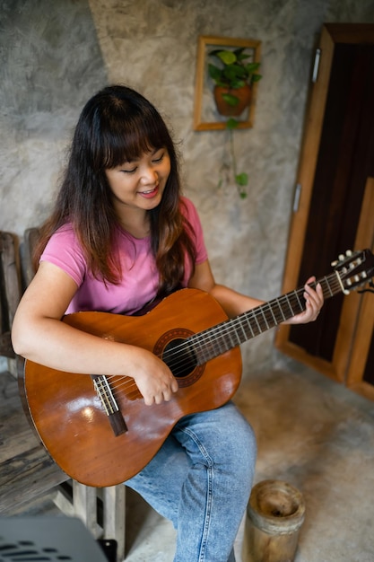 Le mani felici della giovane donna che suonano la chitarra acustica musicista da solo compongono la lezione di canzone strumentale sul suonare la chitarra