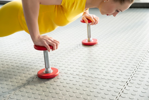 Le mani femminili che tengono la testa di legno esercitano i pesi che stanno sul pavimento in palestra