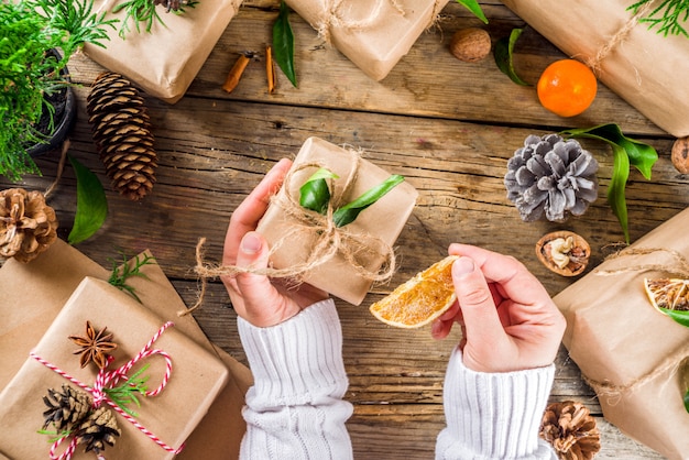 Le mani femminili decorano il contenitore di regalo di natale.