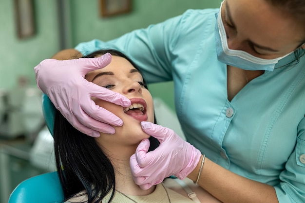 Le mani femminili del dentista esaminano la bocca del paziente, clinica odontoiatrica