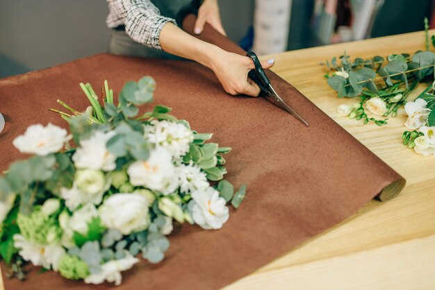 Le mani femminili del fiorista taglia la decorazione floreale con le forbici. Affari floreali, processo di preparazione del bouquet