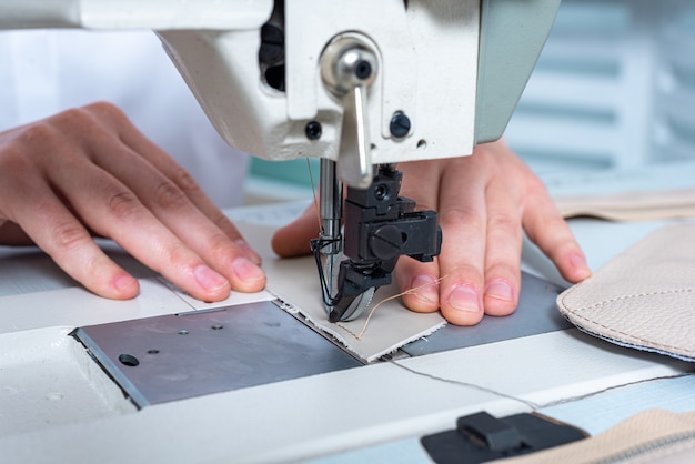 Le mani femminili del primo piano cucono un punto su una macchina per cucire