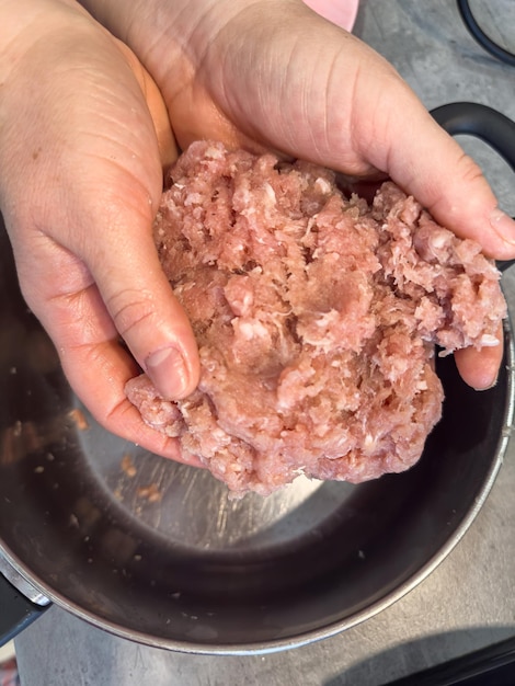 Le mani femminili fanno polpette con il grasso rosso macinato da vicino