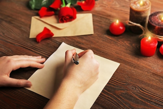 Le mani femminili firmano la carta regalo per il giorno di San Valentino su sfondo di legno