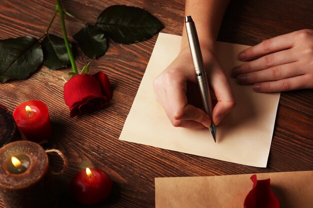 Le mani femminili firmano la carta regalo per il giorno di San Valentino su sfondo di legno