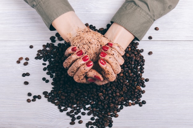 Le mani femminili in caffè sfregano il primo piano