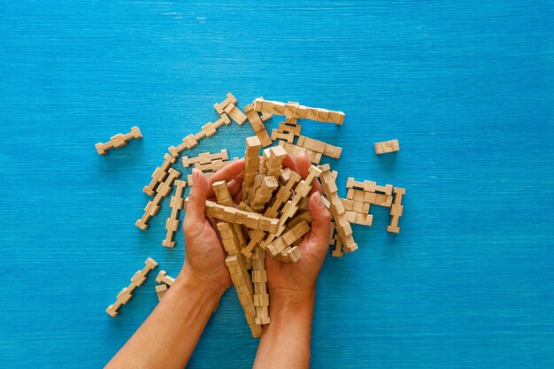 Le mani femminili raccolgono i dettagli di un designer per bambini in legno su sfondo blu