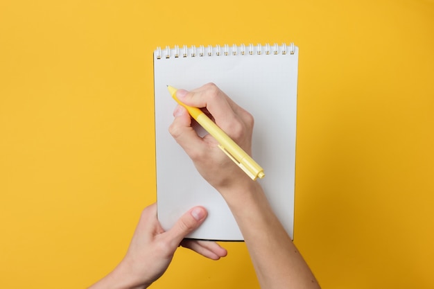 Le mani femminili scrivono con una penna in un taccuino