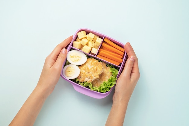 Le mani femminili stanno tenendo un pranzo al sacco di plastica con il pranzo