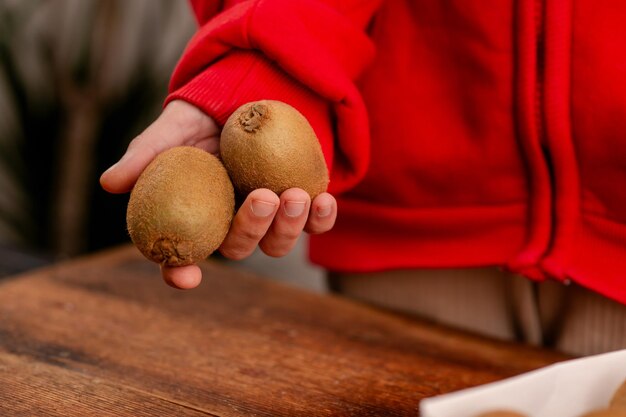 Le mani femminili tengono frutti interi di kiwi presentando la freschezza e il delizioso sapore di questi frutti noti per i loro benefici nutrizionali