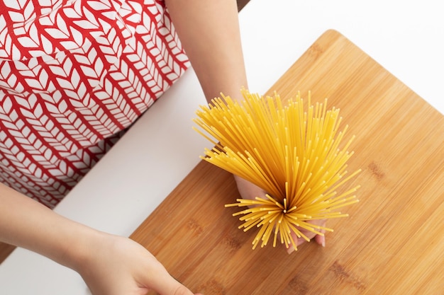 Le mani femminili tengono gli spaghetti non preparati di pasta italiana