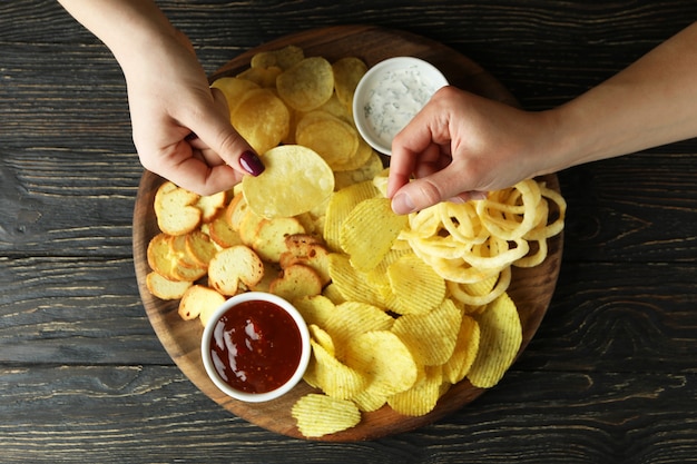 Le mani femminili tengono i chip sopra il vassoio con i chip, vista dall'alto