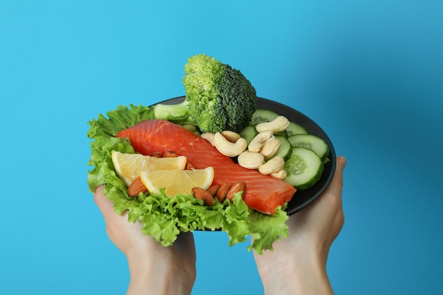 Le mani femminili tengono il cibo sano su sfondo blu