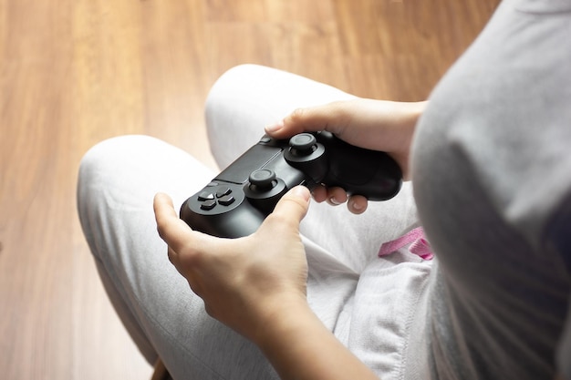 Le mani femminili tengono il joystick una giovane ragazza gioca a un videogioco