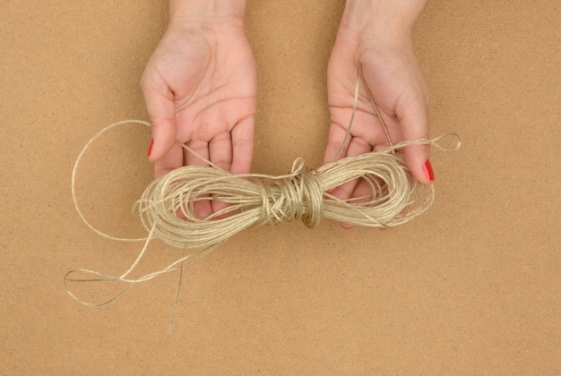 Le mani femminili tengono la corda da bucato aggrovigliata su sfondo marrone