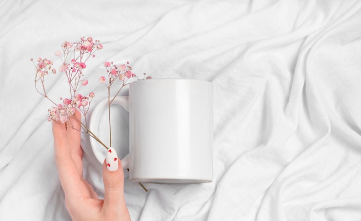 Foto le mani femminili tengono la tazza bianca vuota su una tazza di sfondo tessile per la manicure di san valentino