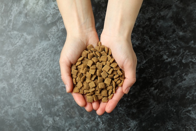 Le mani femminili tengono mangimi per animali domestici su smokey nero