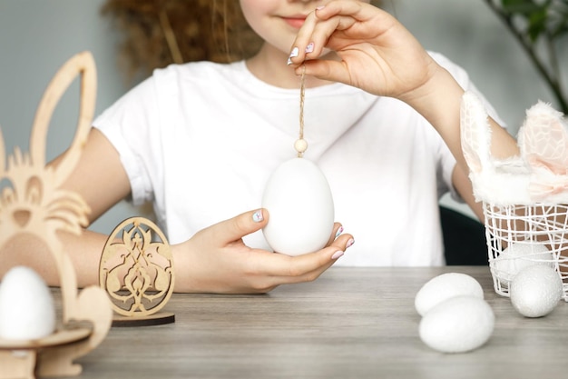 Le mani femminili tengono un uovo bianco su una preparazione di corda per il bianco e nero delle vacanze di Pasqua