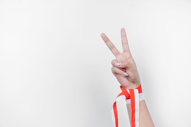 Le mani gesticolano i segni del numero indossando il nastro rosso e bianco indonesiano Concetto di giorno dell'indipendenza dell'Indonesia