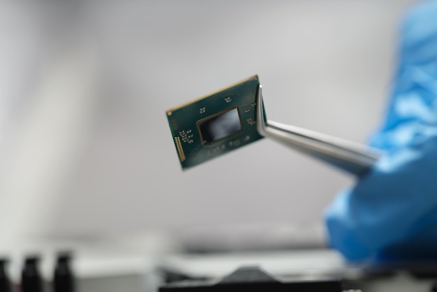 Le mani guantate tengono un microchip con il primo piano delle pinzette