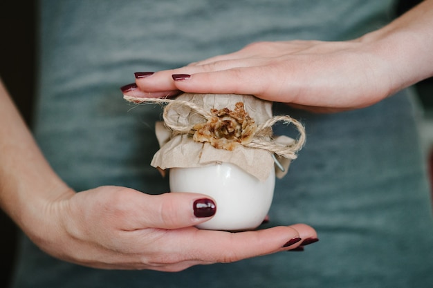 Le mani impeccabili della giovane donna tengono il vasetto cosmetico di crema per la pelle a portata di mano isolato.