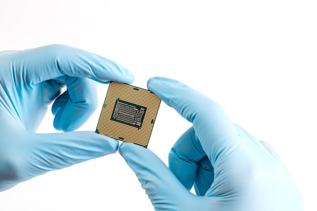 Le mani in guanti blu tengono la CPU del micro processore su sfondo bianco da vicino