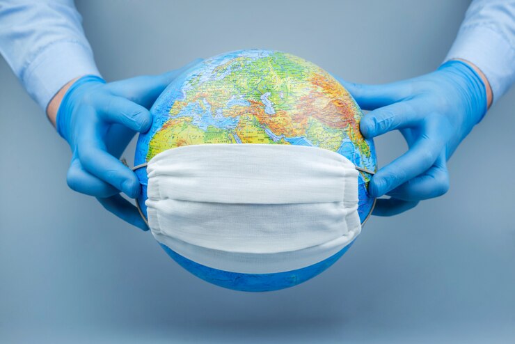 Le mani in guanti medici mettono una maschera protettiva sul globo. Concetto di attacco del mondo Coronavirus / Corona. Concetto di lotta contro il virus.