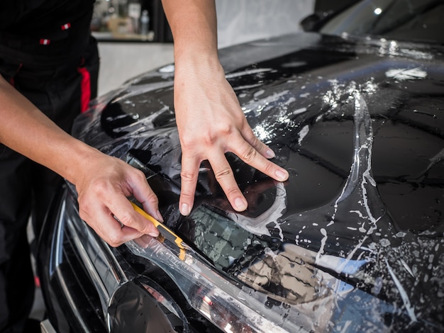 Le mani installa la pellicola di protezione della vernice per auto.