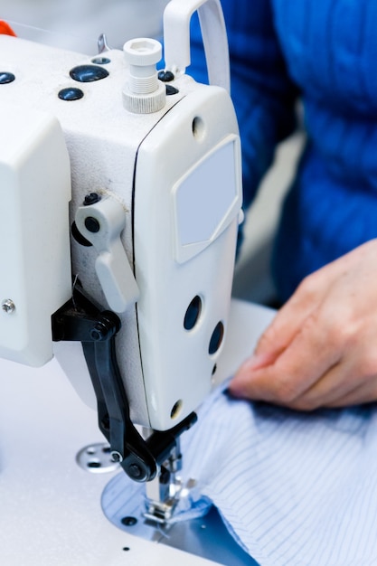 Le mani lavorano una macchina da cucire.