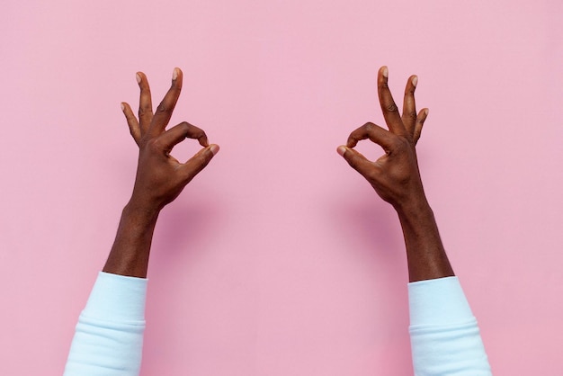 le mani maschili afroamericane mostrano il segno ok sul primo piano rosa isolato del fondo