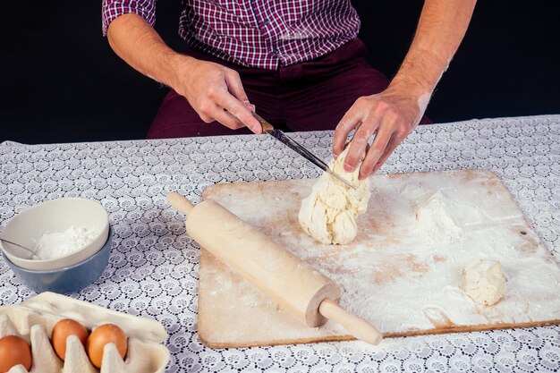 Le mani maschili nella farina e nella pagnotta di pane organica rustica si preparano a fare la pasta italiana bio, pizza, pie