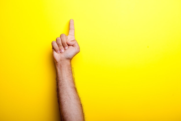 Le mani maschili puntano su sfondo giallo. Foto in studio