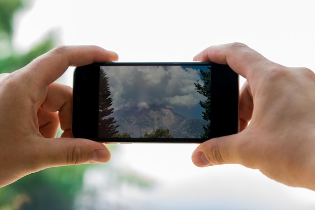 Le mani maschili scattano una foto sul paesaggio montano del telefono