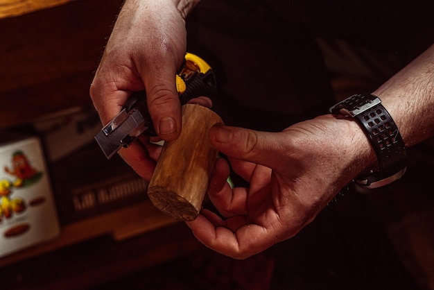 Le mani maschili scolpiscono il legno con un coltello