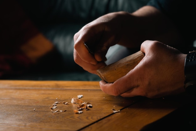 Le mani maschili scolpiscono il legno con un coltello