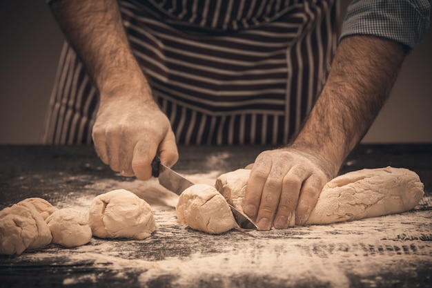 Le mani maschili tagliano la pasta