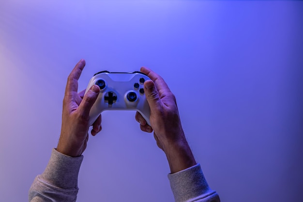 Le mani maschili tengono un gamepad su uno spazio di copia di sfondo blu