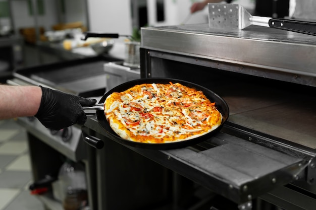 le mani mettono la pizza nel forno