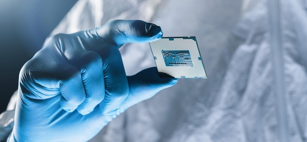 Le mani nei guanti tengono la microelettronica di prova del microchip in una fabbrica di produzione elettronica ultramoderna