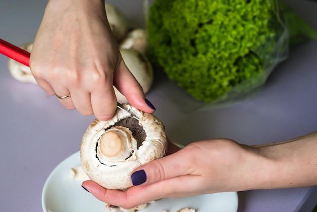 Le mani puliscono i funghi con un coltello