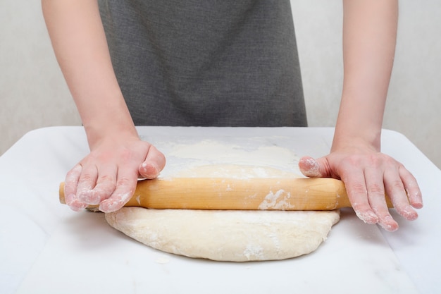 Le mani stendono la pasta con il mattarello