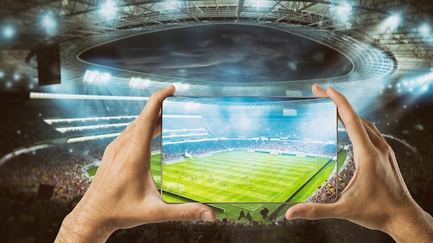 Le mani tengono un cellulare con uno stadio di calcio