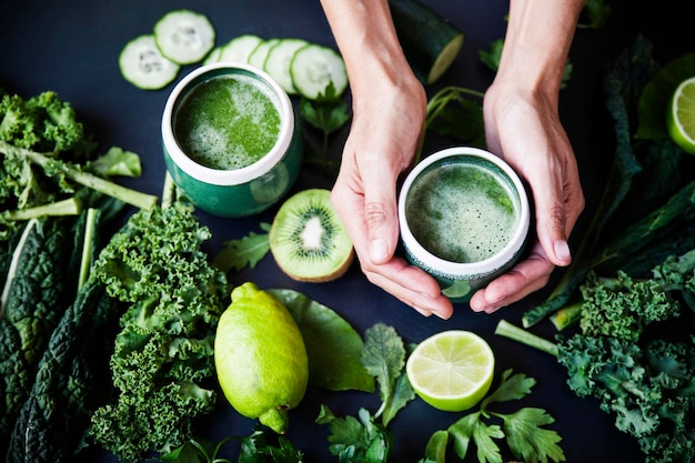 Le mani tengono un succo verde di verdure fresche e crude sane