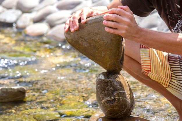 Le mani umane costruiscono un tumulo di pietre sull'acqua. equilibrio e meditazione
