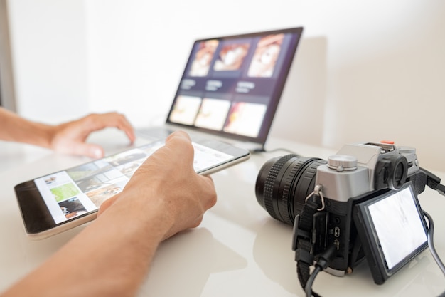 Le mani umane tengono un tablet per organizzare o importare immagini dalla fotocamera al laptop