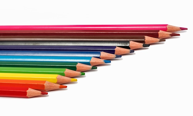 Le matite colorate giacciono in fila su uno sfondo bianco.