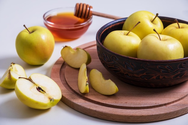 Le mele gialle intere e tagliate fresche mature con miele si trovano sul tavolo. Messa a fuoco selettiva.