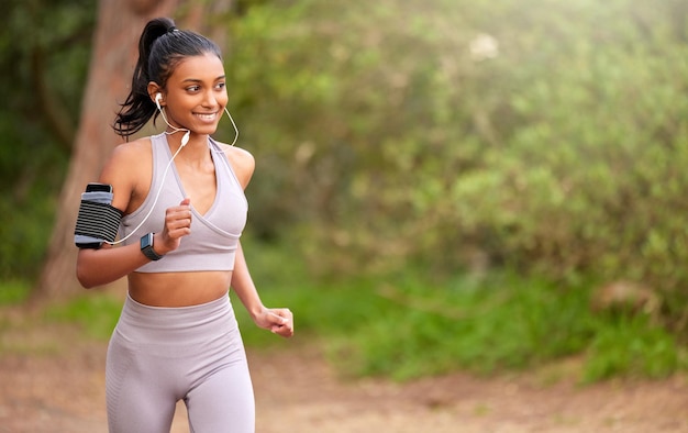 Le melodie giuste per farti commuovere Inquadratura di una giovane donna che fa jogging e ascolta musica mentre si fa strada attraverso una foresta